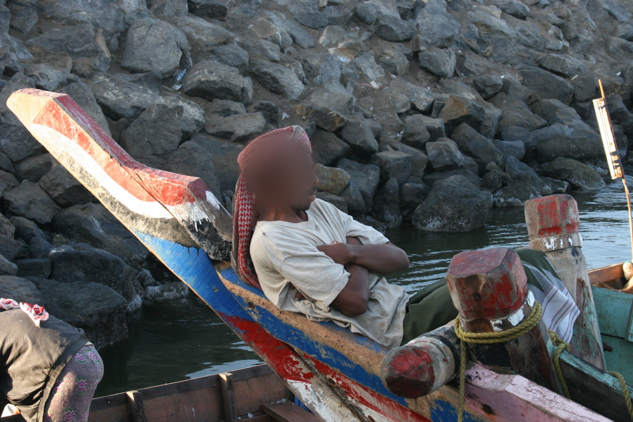 A man sitting in a wooden boat in Yemen with his face blurred