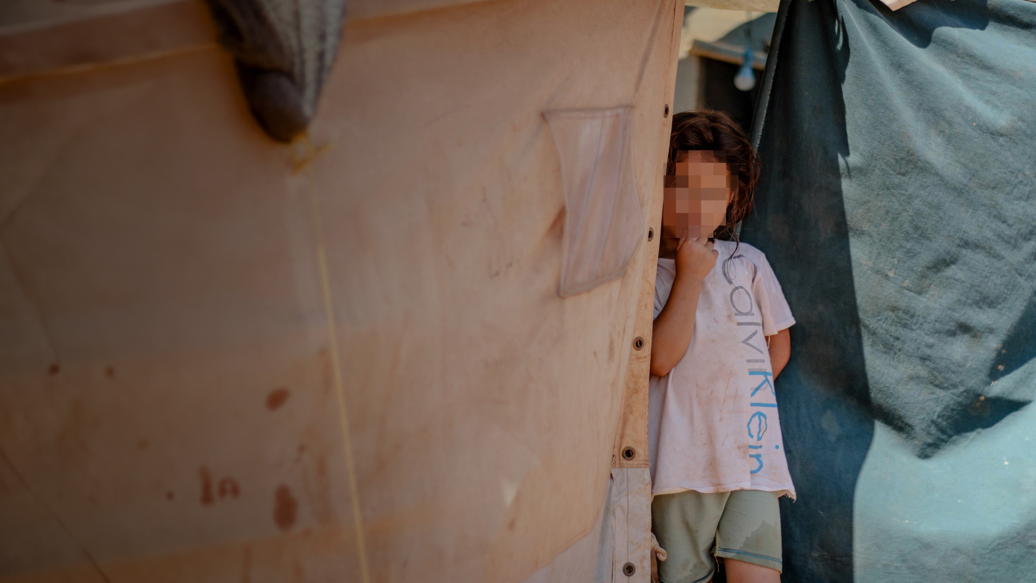 A child standing in the opening of a temporary shelter